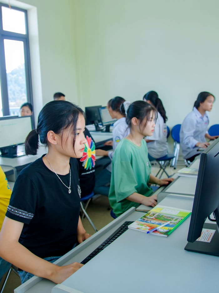 Group of students studying in a computer lab, focusing on teamwork and technology.