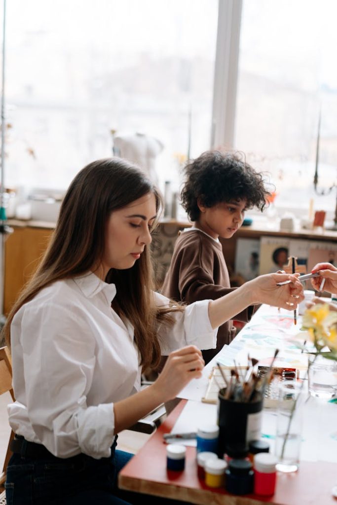 A woman and child engaging in a creative painting session at an art workshop.