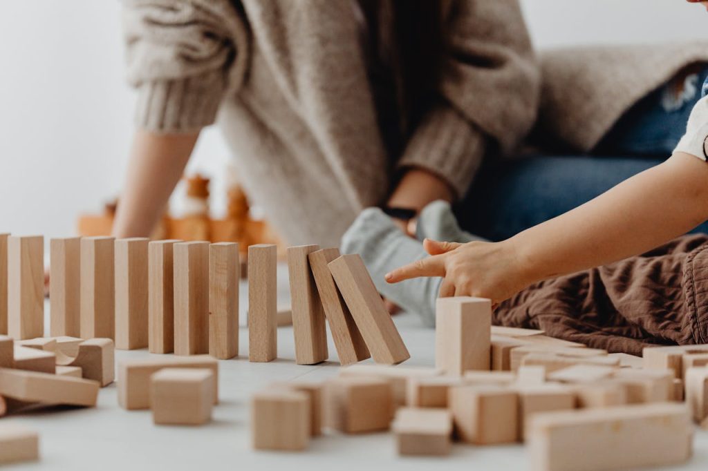Close-up of childs hand tipping over wooden blocks on a table indoors.
